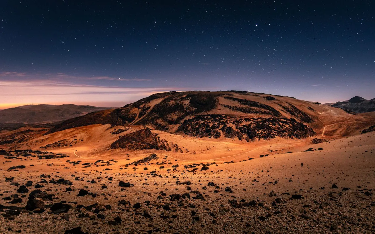 A clear, star-filled night sky over the dark volcanic terrain of Teide National Park